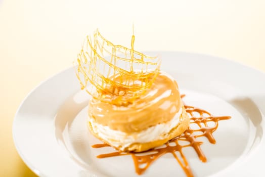 Delicious creamy dessert with caramel topping on yellow background