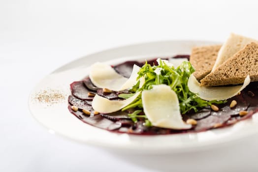 Vegetarian carpaccio with beetroot,nuts and toast on white background