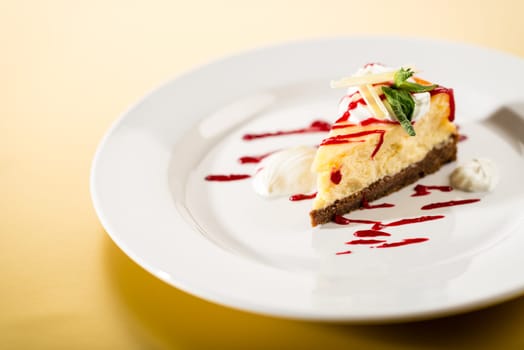 Delicious cheesecake with raspberry sauce on white plate yellow background