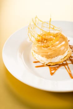 Delicious creamy dessert with caramel topping on yellow background