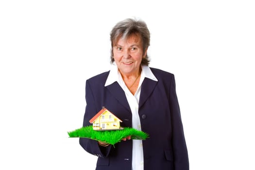 Senior woman with model house on grass mat - isolated on white background