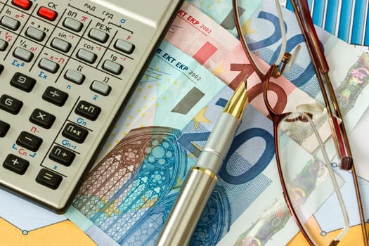 Money, pen, glasses and  calculator on financial diagrams