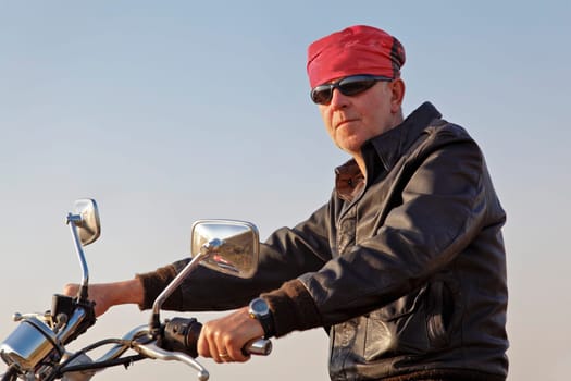 Side on take of white motorbiker posing with sun glasses and red bandanna