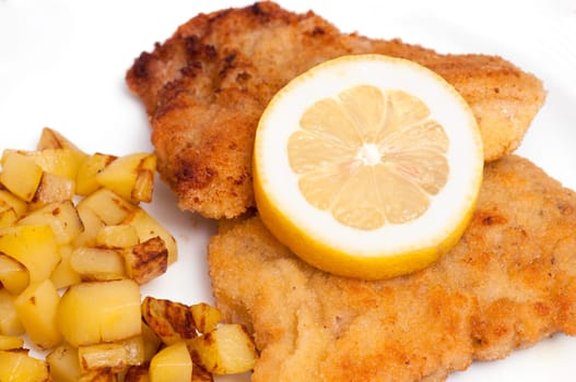 Close-up of a Wiener Schnitzel with lemon slice and small fried potatoes