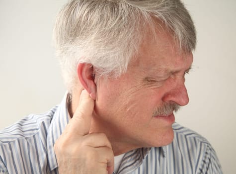 a senior man suffers from pressure behind his ear