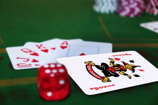 green casino table with dice and a hand of a royal flush in a poker game and a joker in the pack