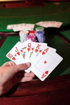 green casino table with a hand of a royal flush in a poker game