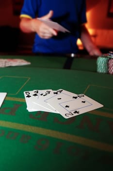 poker player throwing in cards with a straight flush of clubs in the foreground