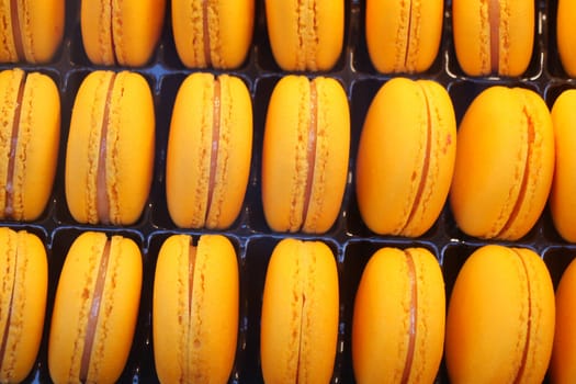Rows of vibrant yellow macarons are showcased in a pastry shop.