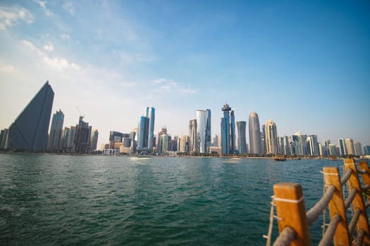 Modern skyscrapers line the waterfront under a clear blue sky.