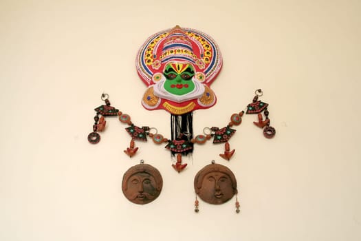 Earthen wall hangings of folk art masks isolated on cream background