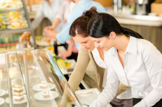 Cafeteria lunch two office colleagues woman choose food dessert self-service