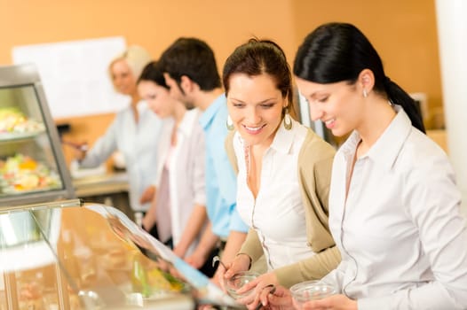 Cafeteria lunch two office colleagues woman choose food buffet self-service