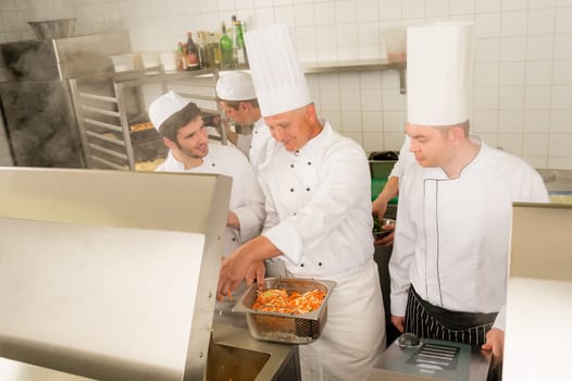 Professional chef cook with team prepare food in industrial kitchen