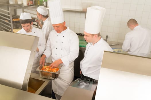 Professional chef cook with team prepare food in industrial kitchen