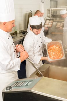 Professional chef cook with team prepare food in industrial kitchen