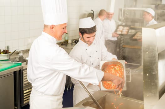Professional chef cook with team prepare food in industrial kitchen