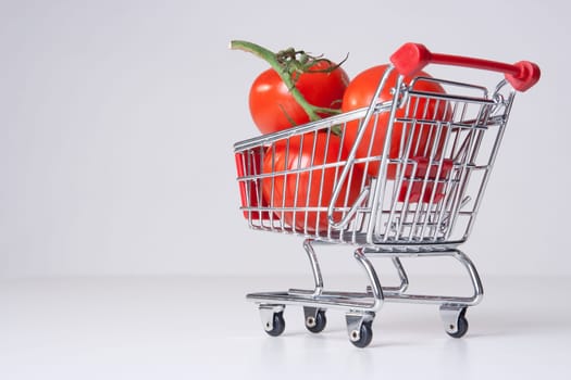 Buy fruit and vegetable concept (could be used for genetically modified food, GM food). Shopping cart (shopping trolley) with big tomatoes.