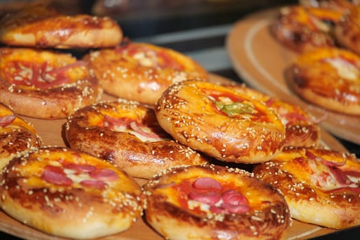 Delicious pastries topped with cheese, meats, and herbs at a bakery.