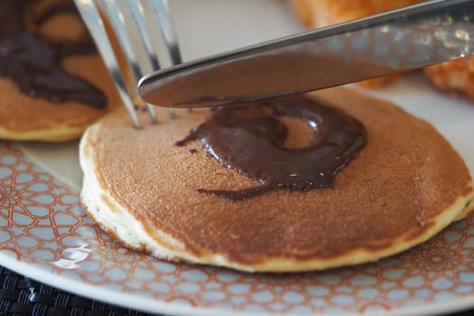 Fluffy pancakes topped with rich chocolate spread during breakfast time.