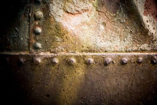 Grungy surface texture of rusted weathered old iron with rivets joining the plates of metal