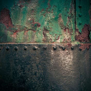 Grungy rusty old iron texture with weathered green paint and a riveted join with vignetting