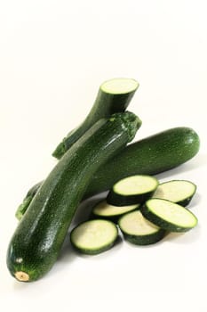 three green zucchini against white background