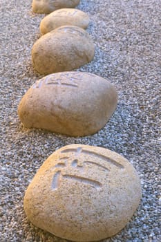Boulders carved with Chinese characters lying in the gravel.