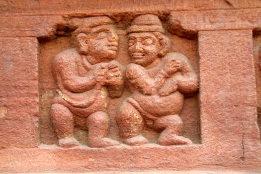 Stone carving of dwarfs on the base wall of cave temple at Badami in Karnataka, India, Asia