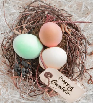 Three boiled dyed Easter Eggs in a nest with a Happy Easter tag.