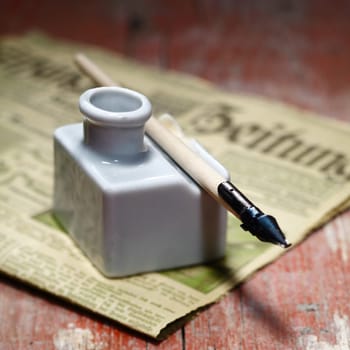 Old Ink Quill and an antique newspaper on an ancient wooden background