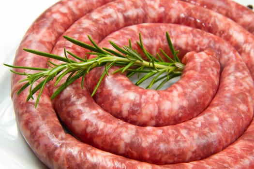 fresh raw sausage with rosemary on white dish