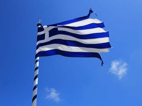 Used greek flag teared up and blue sky with little cloud background