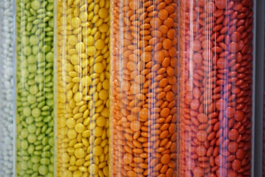 Brightly colored candies arranged in tall transparent containers at a market.