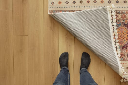 The rug is being pulled back to reveal the wooden floor beneath.