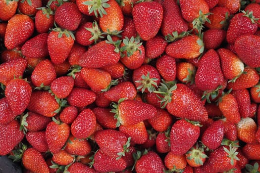 Baskets of ripe strawberries are displayed at a vibrant summer market.