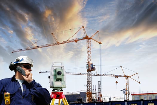construction engineer working with measuring instrument, building site in background, sunset.