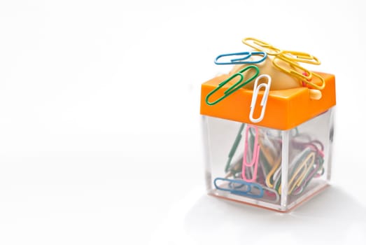 Colorful plastic coated paper clips in clear innovative container with magnet, isolated on white background