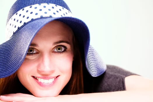Laughing woman in summer hat against light green background