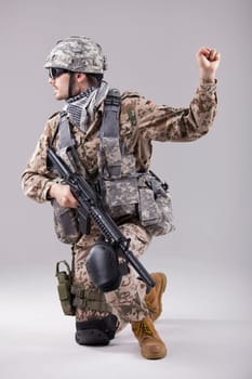 armed soldier kneeling with hand warning or stop gesture