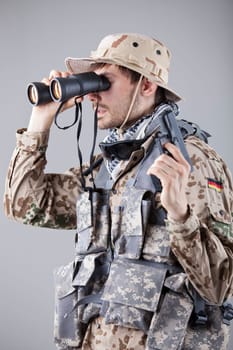 Soldier with handgun looking through binoculars
