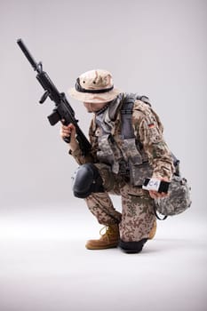 Armed Soldier in camouflage with explosive in his hand - shot in white studio