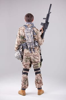 Soldier with machine gun - shot from behind over white
