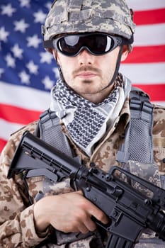 Portrait of armed american soldier in camouflage over american flag