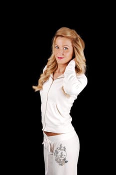 A portrait shot of a young beautiful woman with long blond hair, in a white tracksuit standing for black background.