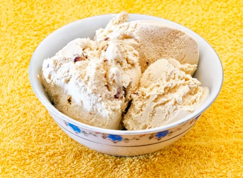 vanilla ice cream with nuts in a container on a yellow background