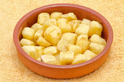 Fried pieces of potatoes with oil , dill pepper and salt. plate with typical spanish patatas bravas.