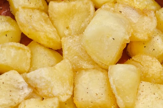 Fried pieces of potatoes with oil , dill pepper and salt. plate with typical spanish patatas bravas.