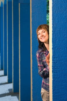 Upper body portrait of a young brunette woman posing between blue architectural pillars