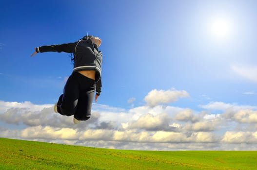 Woman jumping high in a green field